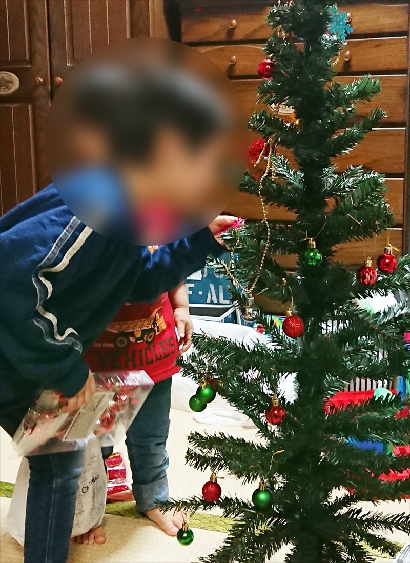 子供がクリスマスツリーに飾り付け